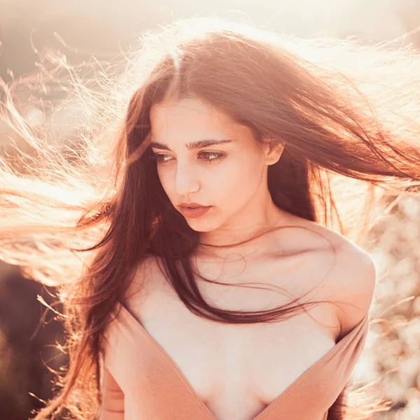 Girl with decollete enjoy her hair waving by wind. Woman on calm face enjoy sunny and windy day, nature on background, defocused. Lady looks attractive with waving long hair. Hair care concept. — Stock Photo, Image