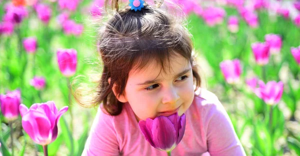 Obličej a péče o pleť. alergie na květiny. Malé dítě. Přírodní krásy. Den dětí. Malá holčička v jarní Slunečné. Letní móda dívka. Šťastné dětství. Jarní tulipány. Předpověď počasí. Zelené rostliny — Stock fotografie