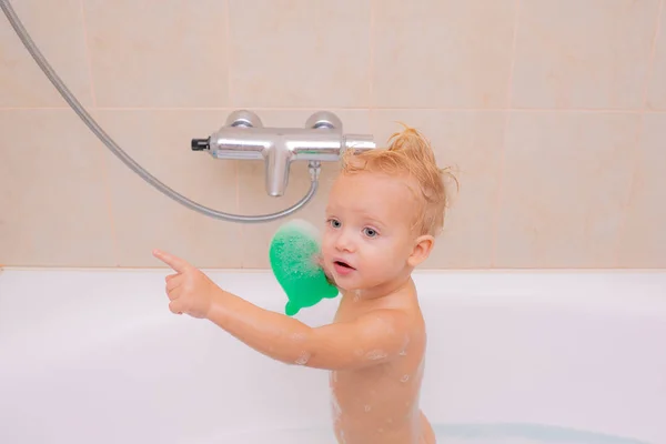 Kinderbad. Ein einjähriges Baby badet in der Dusche. Badespielzeugente. glücklicher kleiner Junge, der Spaß beim Baden hat. — Stockfoto