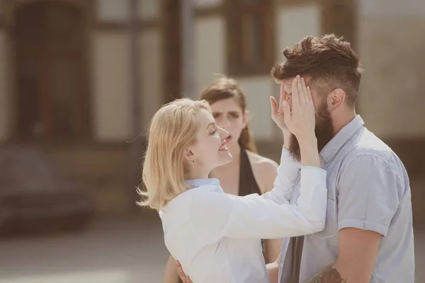 Shes jealous of their relationship. Jealous woman look at couple in love on street. Romantic couple of man and woman dating. Bearded man cheating his woman with another girl. Unhappy jealous girl — Zdjęcie stockowe