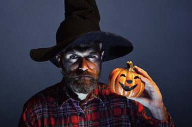 Cadılar Bayramı Balkabağı mavi arka plan üzerinde tutarak cadı şapka erkekte