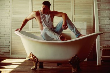 Banyo, hijyen adam. Seksi maço kolsuz bluz ve kot moda. Banyo adam otur. Fitness modeli güçlü beden sağlığı ile. Hijyen ve banyo kavramı