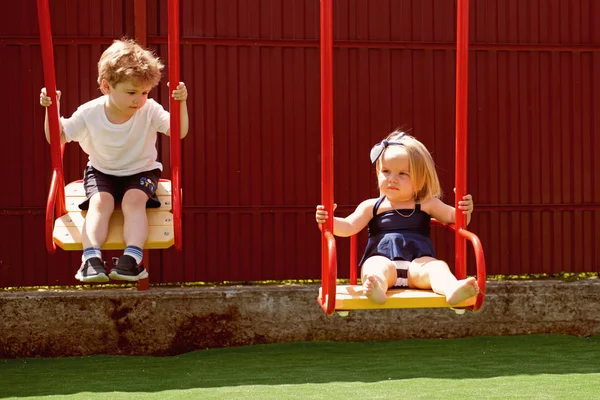 どこ私たちが育ちます。スイングでブロンドの髪と小さな子供。小さな弟と妹は、一緒にプレーをお楽しみください。女の子と男の子のヘアカット スタイル。子供のための美容室。何か新しい、別 — ストック写真