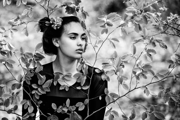 Menina com flor no cabelo em folhas de árvore verde — Fotografia de Stock