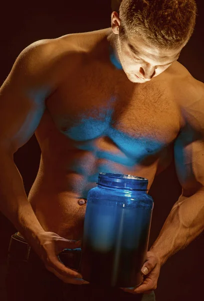 Healthy diet and fitness. Man use sport vitamin supplements for muscle building. Sport nutrition and vitamin diet. Athletic man open vitamin bottle with led light in strong arms. Keeping you strong