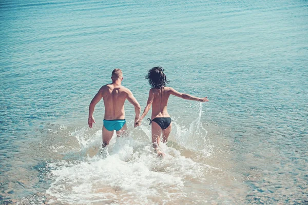 Divertirse, diversión y felicidad de la joven sexy pareja correr y va a nadar en el agua de mar . — Foto de Stock