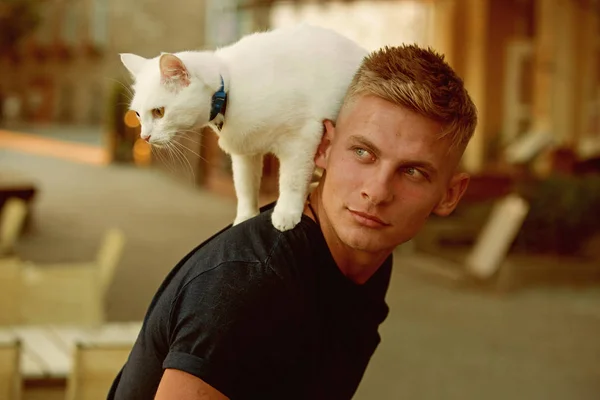 Curious explorer. Happy man on walk with cat pet. Muscular man hold cute pedigree cat. Happy cat owner with muscular look. Cat stands on back of his owner