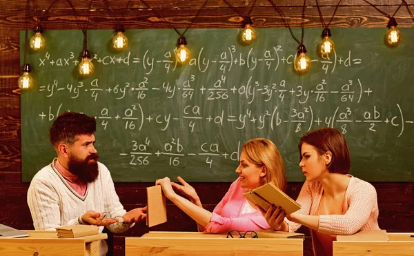 Girls students and bearded teacher, lecturer, professor. College and education concept. Students, young scientists studying, holds book , while professor teaches, explains, chalkboard background — Stock Photo, Image
