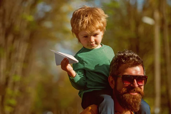 Padre e hijo lanzan avión de papel en el parque, soñando concepto. Niño pequeño soñando con viajar en avión. No hay mejor manera de volar — Foto de Stock