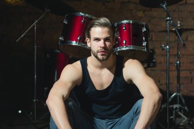 Davul ritmini. Rock yıldızı ya da rock'çı. Enstrümantal müzik keyfi. Yakışıklı adam vurmalı enstrüman aşamada oturamaz. Müzik aleti, adam davulcu. Rock konseri ya da prova müzik kulübü