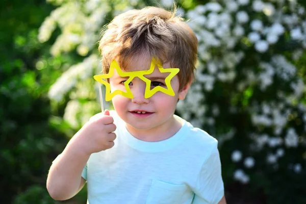 Criança pequena com óculos de festa de verão. Criança na floresta verde. Férias. Tempo ensolarado. Criança feliz na natureza florescente. Felicidade infantil. Dia das crianças. Primavera na minha cabeça — Fotografia de Stock