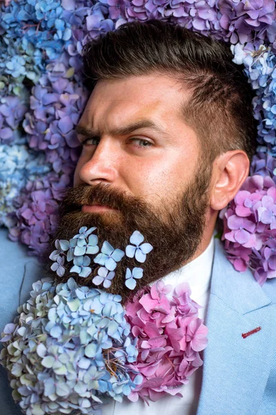 Volwassen hipster met baard. Gezond haar en huid. man met bloemen van de hortensia. lente. Womens dag. brutale Kaukasische hipster met snor. Bebaarde man. Zomer. In zijn eigen stijl — Stockfoto