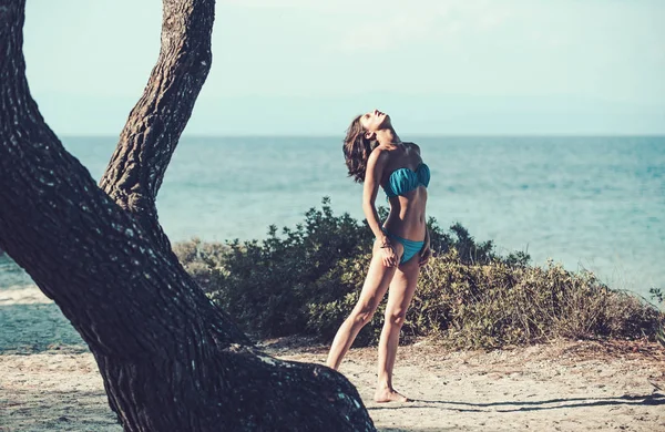 Mannequin de mode en maillot de bain sanbathing en mer près de l'arbre. été de femme sexy. femme heureuse se détendre en mer. Vacances d'été et vacances de voyage. fille sexy profiter du soleil à la plage . — Photo