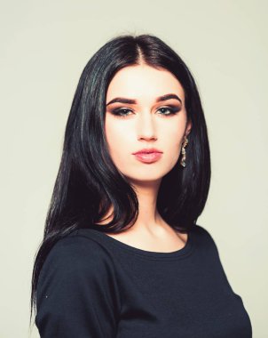 Studio poz uzun siyah saçlı güzel genç kadın. Gri arka plan üzerinde izole dumanlı gözlü esmer portresi.