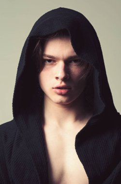 Siyah hood, gri arka planda emin yüz adam. Pürüzsüz cilt yüz, boyun ve göğüs kameraya bakarak üzerinde olan adam. Erkeklik kavramı. Maço siyah bornoz ile kukuleta, yakın çekim