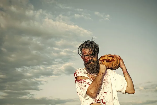 Halloween hipster celebración de la calabaza en el cielo azul nublado — Foto de Stock