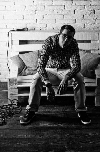 adam gözlük ve mikrofon ile bankta kareli gömlek