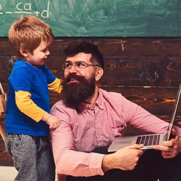 Gülümseyen Baba oğlunu bilgisayar becerilerinin öğretimi. Baba ve oğul birbirine bakarak. Oturan babası boynumdan sarılmayı çocuk ayakta