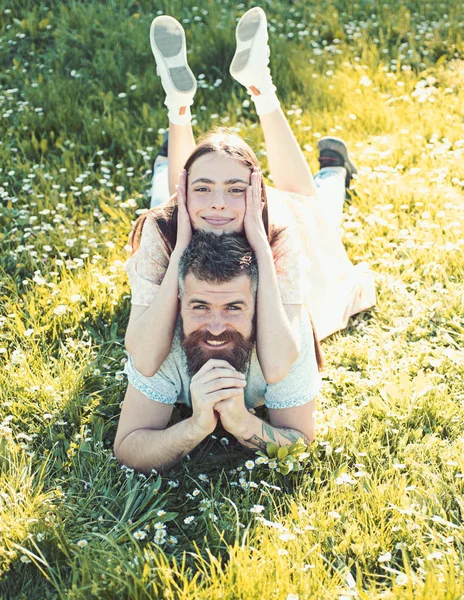 Man and woman laying on grass spring day. Spring leisure concept. Couple on happy smiling faces laying at meadow, nature on background. Couple in love spend time outdoors and hugs.