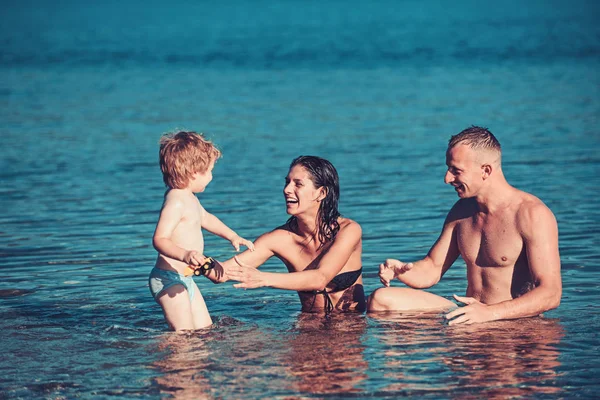 父と息子と母はビーチに海で泳ぐ。父と海や海の水で幸せな子供を持つ母. — ストック写真