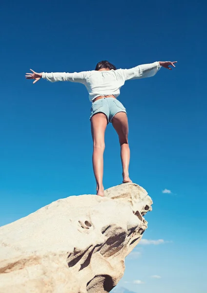 Bakifrån av en vacker, brunett ung flicka med upphöjda händer, titta på havet. Frihet koncept, semester på stranden med klar himmel bakgrund — Stockfoto