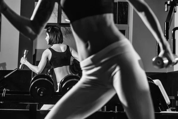 Frauenbeine in gelben Hosen beim Training mit Metallic-Kurzhanteln — Stockfoto