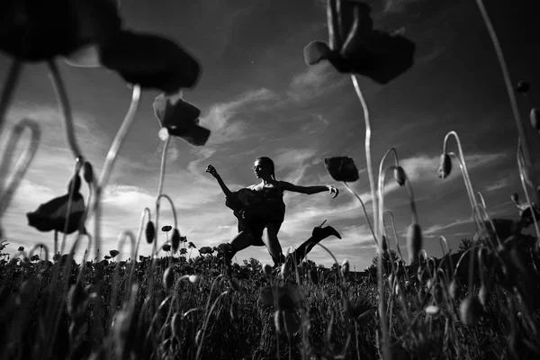 Girl jumping in flower field of poppy seed — Stock Photo, Image