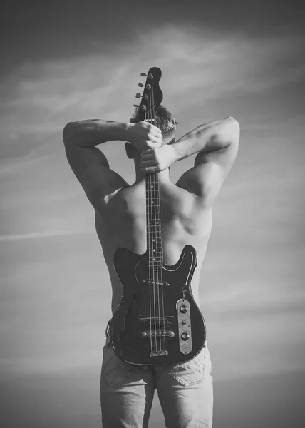 Sportsman med muskulös tillbaka håll elgitarr — Stockfoto