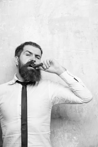 Бородатый мужчина на серьезном лице курит сигару — стоковое фото