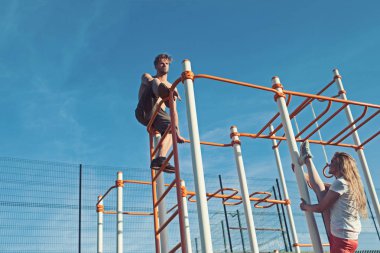 Adam atlet üst ve kadın split bacak üzerinde tırmanmaya. Çift eğitim metal orman spor salonunda spor. Sporcu ve sporcumuz maymun barlarda. Spor pilates ve egzersiz kavramı