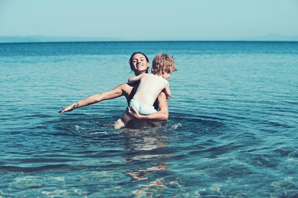 水で息子のスイミングの母。カリブ海の幸せな家族。夏休み、海への旅行。モルディブまたはマイアミ ビーチ活動の喜び。母親女親の手で少年の日の休日. — ストック写真