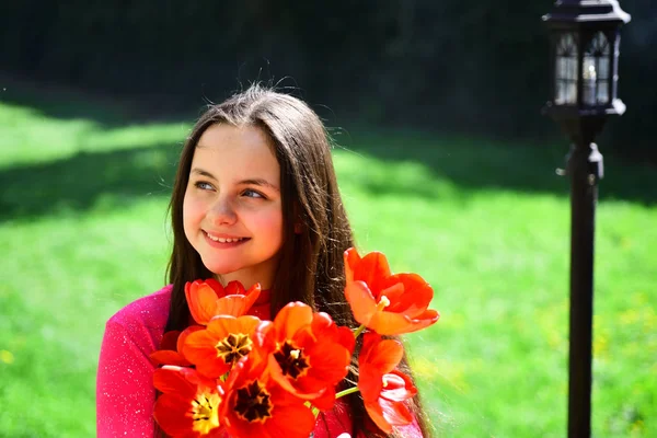 Прекрасний і ароматний. Красива дівчина з квітковим букетом. Мила дівчинка з червоними квітами тюльпанів у весняний день. Маленька дівчинка з квіткою. Святкування 8 березня або жіночого дня. Цвітіння навесні — стокове фото
