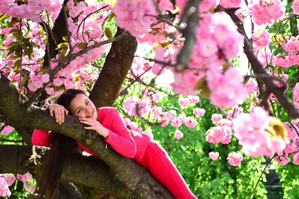 Her individual style. Fashionable young lady on flowering tree. Little girl in fashion wear in spring garden. Pretty girl with fashion look. Fashion clothing for spring