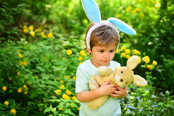 Caça ao ovo nas férias da primavera. Criança na floresta verde. Adoro Páscoa. Férias em família. Feliz Páscoa. Infância. Um miúdo coelho com orelhas de coelho. Brinquedo de lebre. Diversão de Páscoa — Fotografia de Stock