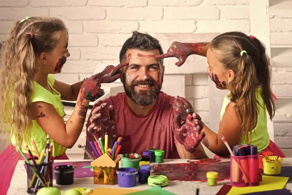 Daughters and dad smiling with painted hands