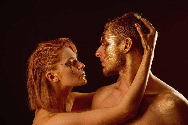 Sexy couple with golden body art makeup isolated on black. Gold spa and skincare treatment. Man and woman relations. Golden collagen mask and beauty. 24K Gold. Erotic games of couple in love