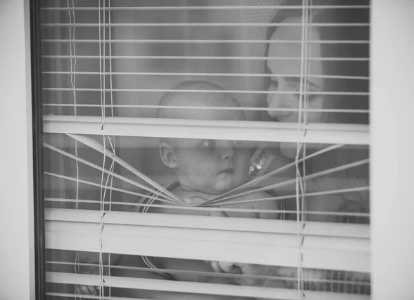 Mãe com bebê filho olhar através de persianas — Fotografia de Stock