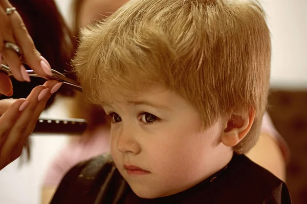 Rendre la coupe amusante. Un petit enfant se fait couper les cheveux. Petit enfant dans le salon de coiffure. Petit garçon aux cheveux blonds chez le coiffeur. Jolie coiffure de garçon. Salon de coiffure pour enfants. Ayant la coupe courte — Photo