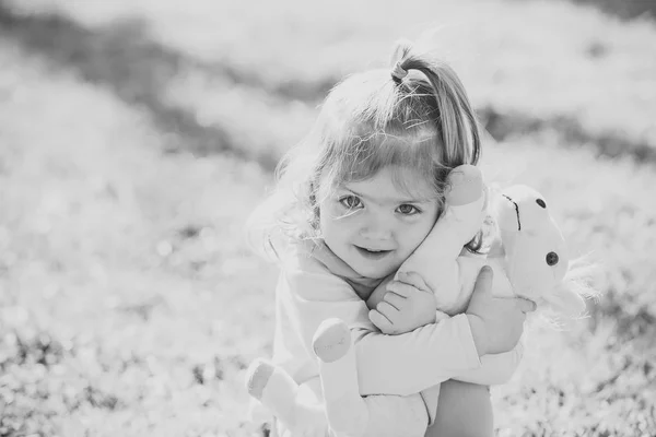 Kid girl hug soft horse toy on sunny day — Stock Photo, Image