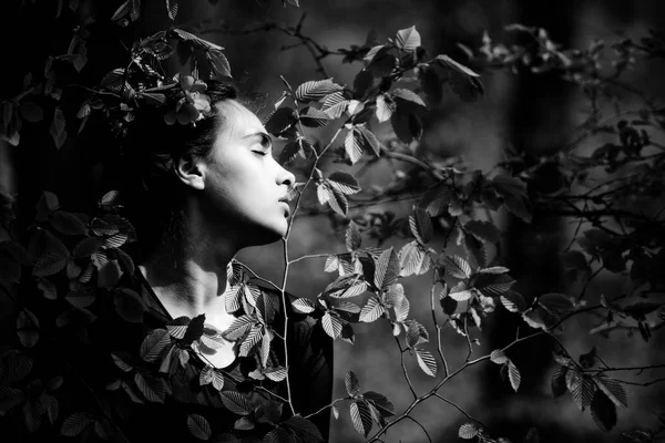 Frau mit Blume im Haar in grünen Baumblättern — Stockfoto