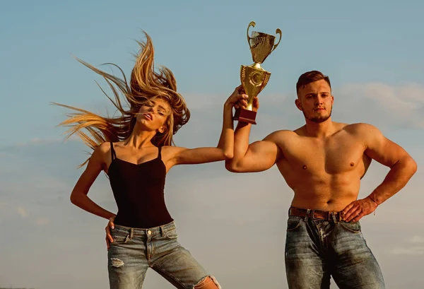 Champions celebrate victory. Athletic champions with golden cup on blue sky. Champions won competition. Woman and man champions. Winners never quit and quitters never win