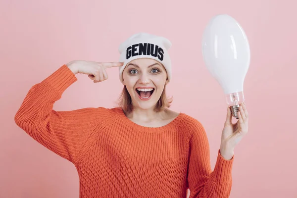 Beautiful minds inspire others. Happy woman hold light bulb pointing at head. Sensual woman wear hat with genius word. Girl genius got bright idea. A genius idea came into her head — Stockfoto