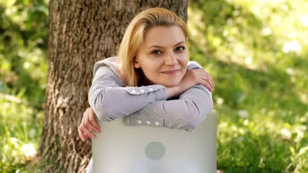 Primer plano de una estudiante con un portátil en el parque. La chica sonríe sinceramente. Chica emocionada en el parque . — Vídeos de Stock