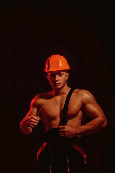 In bewaring. Gespierde man met nagel. Bouwvakker of bouwer met biceps, triceps. Sterke man met gespierde armen. Werknemer of workman in harde hoed. Hard werken — Stockfoto