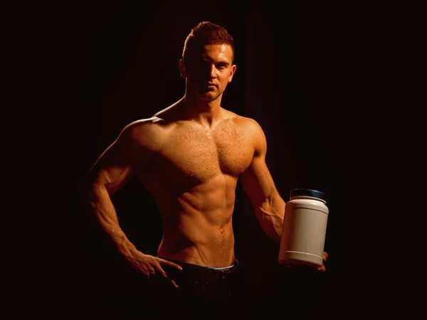 Odżywianie i witaminy dieta Sport. Człowiek Użyj sport witaminy suplementy dla budowy mięśni. Lekkoatletycznego mężczyzna trzymać butelkę witaminy w silnych ramionach. Zdrowa dieta i fitness. Witaminy dla budowania mięśni — Zdjęcie stockowe
