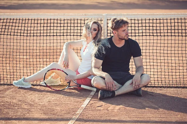 训练结束后, 情侣们在网球场上放松身心。运动员和女运动员坐在网前。网球运动员在黏土表面休息。体育游戏和健康概念 — 图库照片