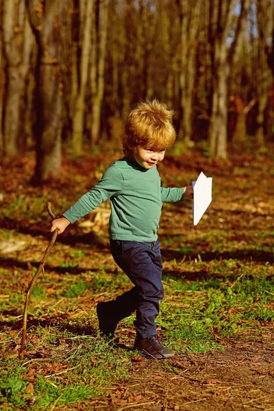 Brinquedo de avião de papel de lançamento de menino pequeno ao ar livre. Criança brinca com brinquedo no parque. Tempo de sobra, ir pelo ar — Fotografia de Stock