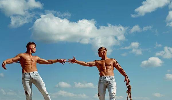 Preparado para la victoria. Los hombres muestran su fuerza contra los competidores. Gemelos atléticos en lados opuestos. Gemelos competidores con cuerpos musculares. Hombres fuertes tiran de la cuerda con fuerza muscular de la mano — Foto de Stock