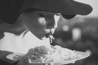 restaurant critic tatse italian pasta. restaurant, woman with red lips in black hat eating pasta. clipart