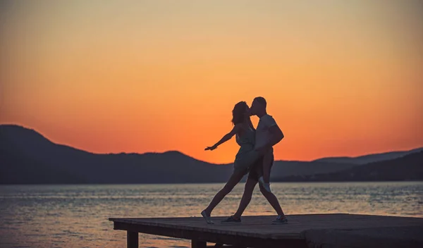 Verliebte Paare tanzen am Strand von Sonnenaufgang. Verliebte Paare tanzen in der Dämmerung auf der Seebrücke. — Stockfoto